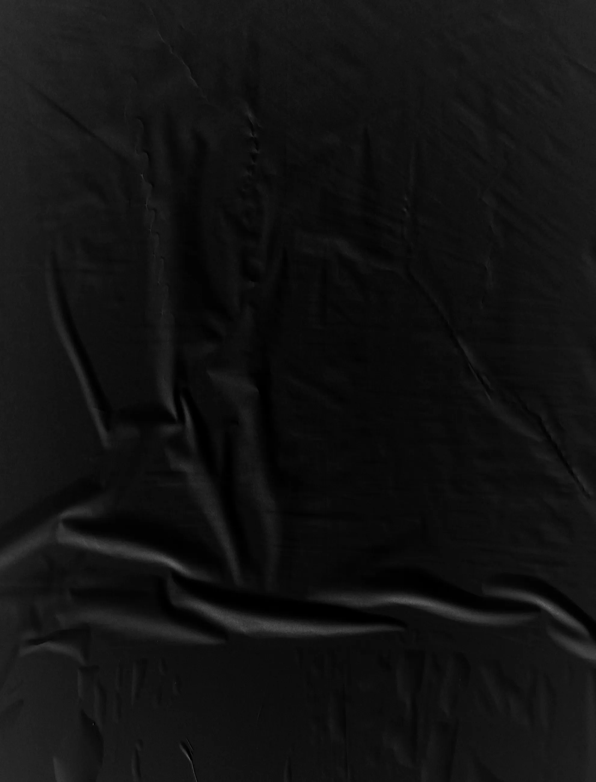 Black fabric with visible folds and wrinkles.